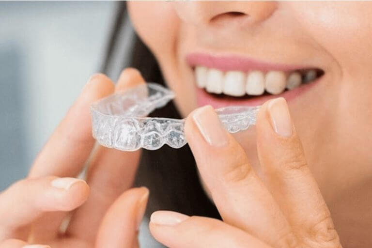 woman holding Invisalign aligners in front of her teeth at Beeston Dental Practice